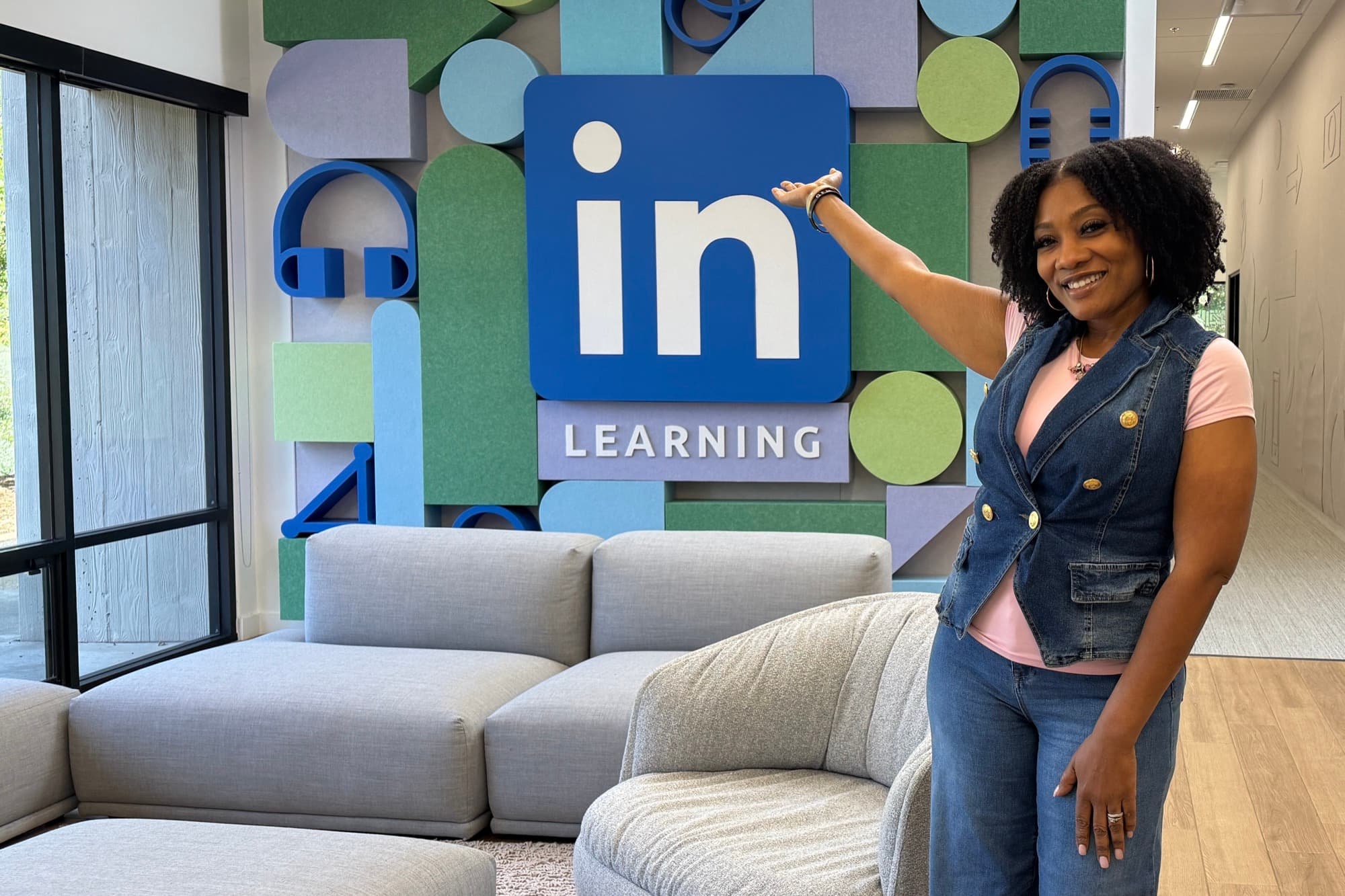 Tiffany Teasley at LinkedIn's offices, resting a hand on the LinkedIn Learning sign.