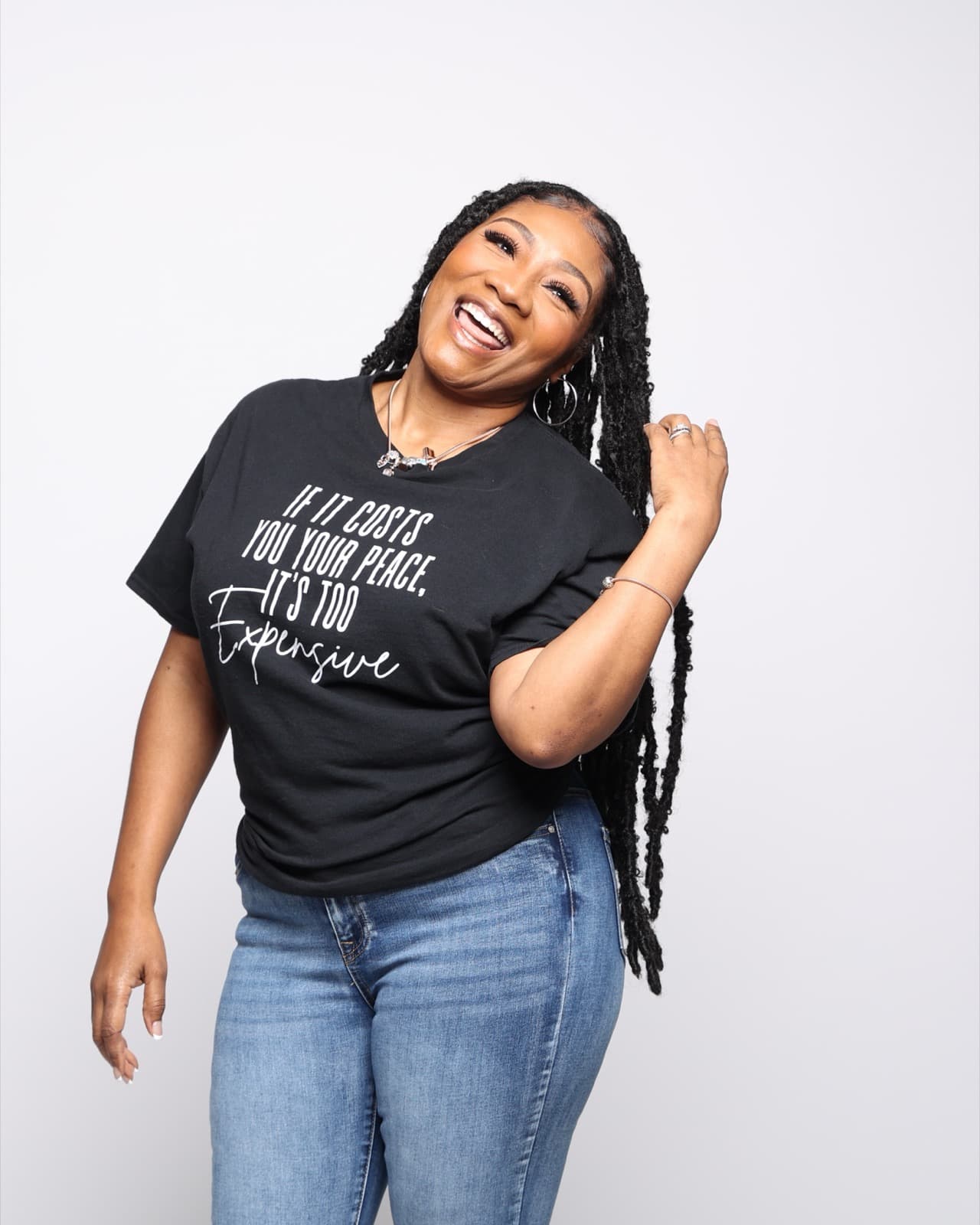 Tiffany Teasley laughing, in a black T-shirt reading “If it costs you your peace, it’s too expensive.”